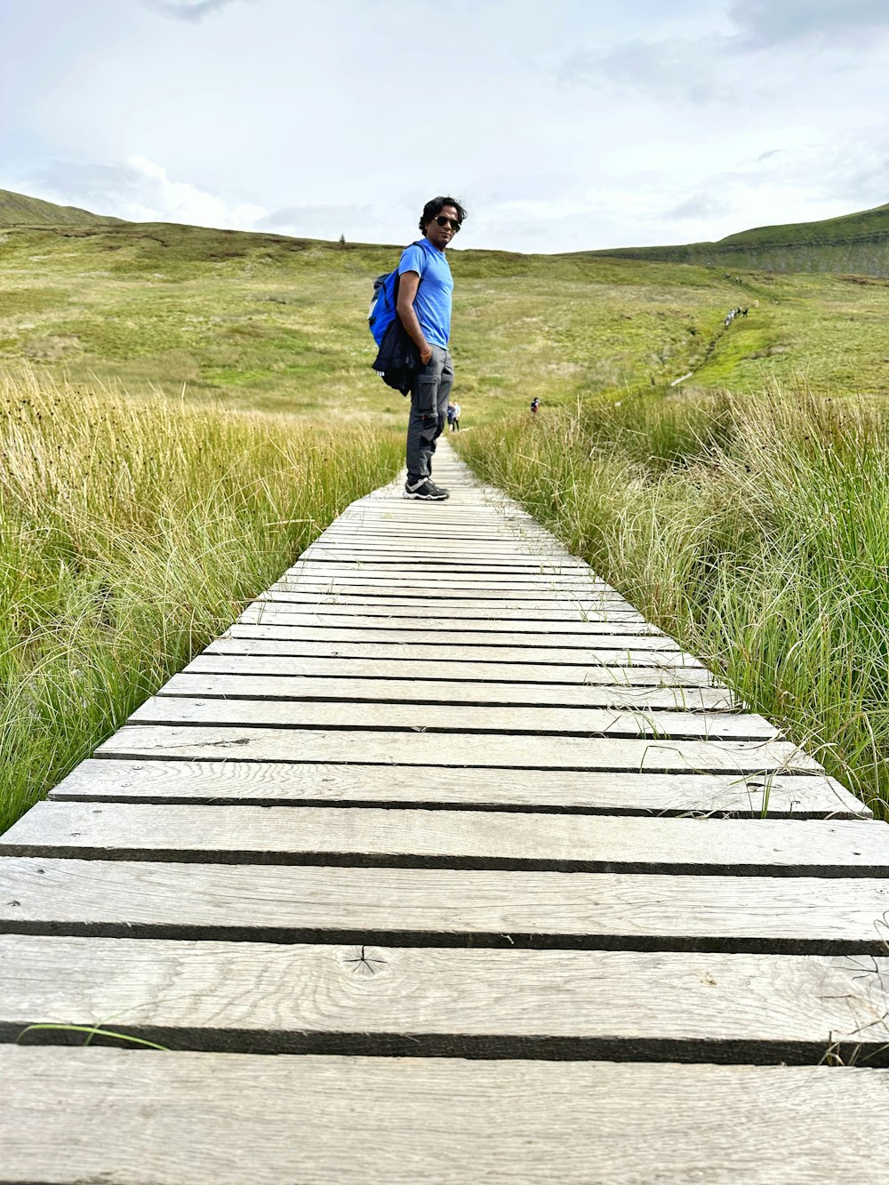 a man standing on a wooden walkway in a field