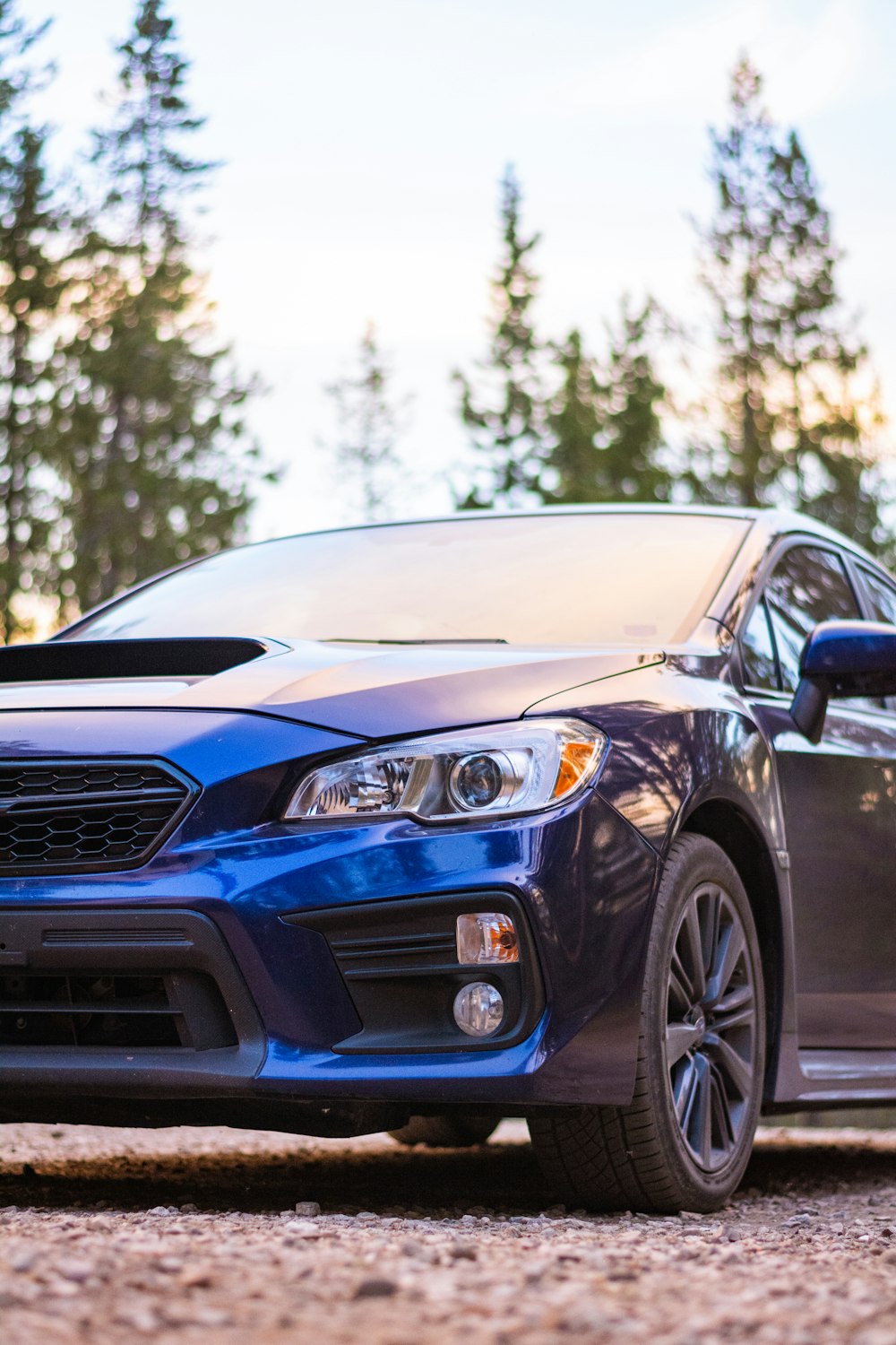a blue subarunt parked on a gravel road