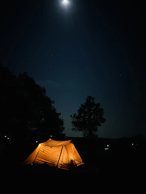 A bubble tent glowing softly under the stars, surrounded by nature.