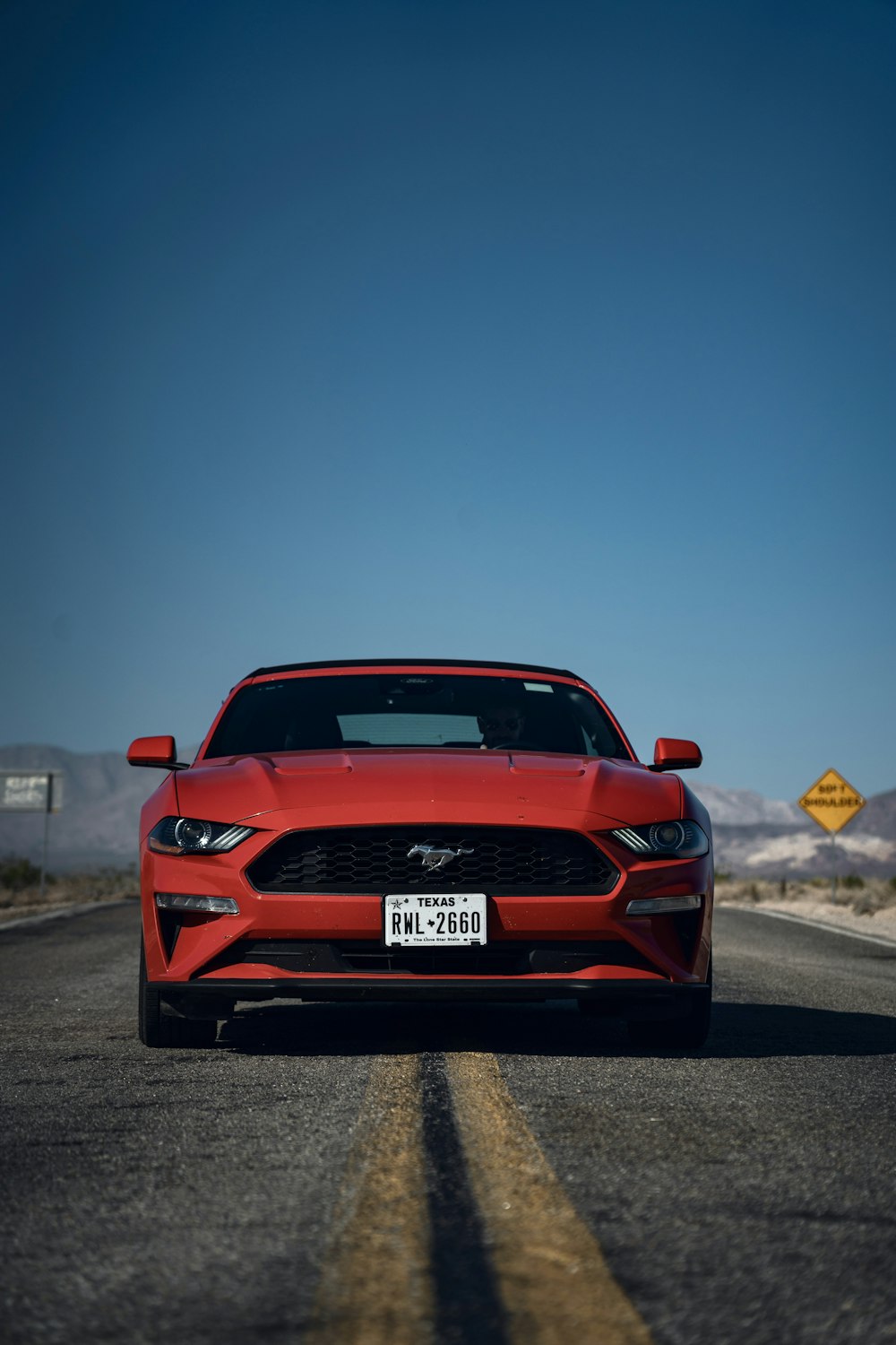 a red mustang car driving down the road