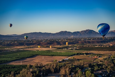 A colorful hot air balloon floating above a patchwork of green fields.