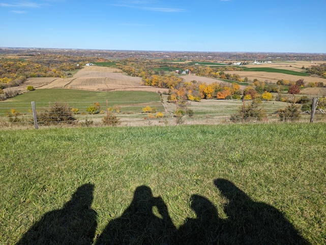 A warm, slightly blurred background showing diverse people collaborating in rural and urban settings—farmers in fields, teachers in classrooms, healthcare workers in outreach, and youth in community meetings, all bathed in natural greens, blues, and earth tones.