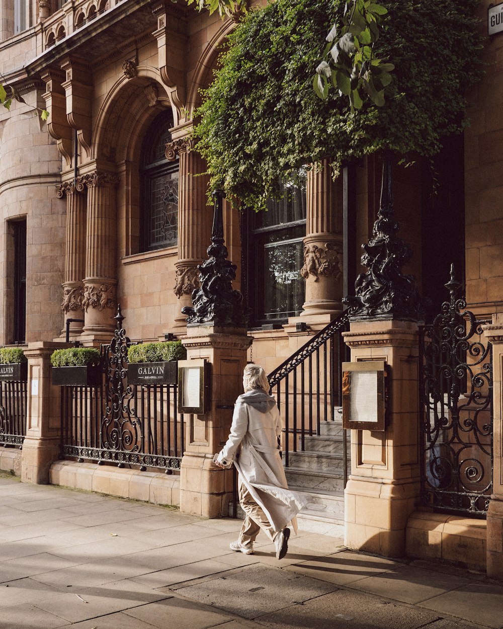 a woman walking down a sidewalk next to a tall building