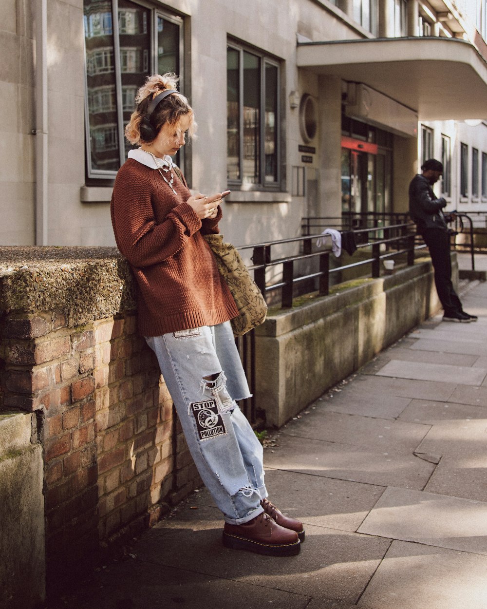 a woman leaning against a wall using a cell phone