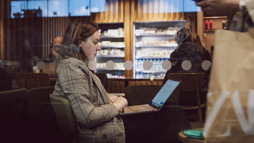 uma mulher sentada em uma cadeira usando um computador portátil