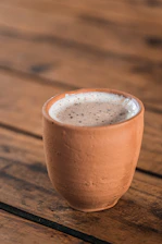 Decorative clay cups arranged on a rustic wooden table with steam rising.