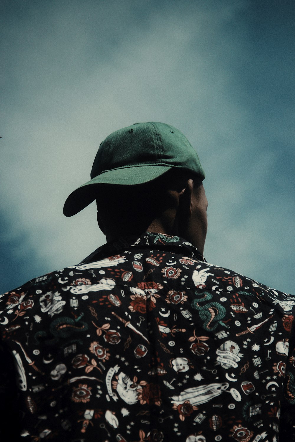 a man wearing a green hat looking up into the sky