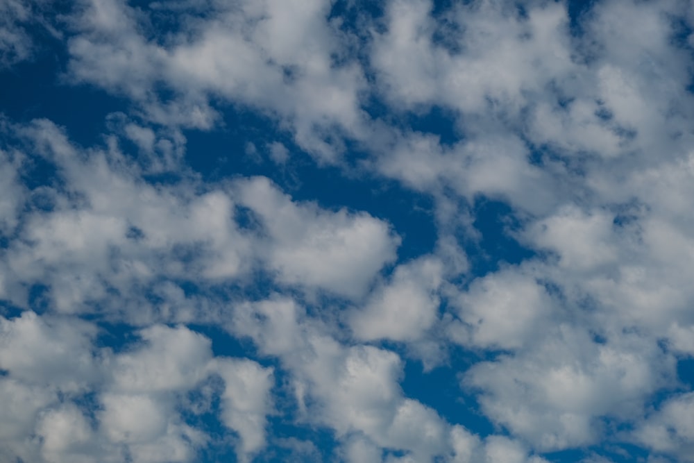 a plane flying through a cloudy blue sky