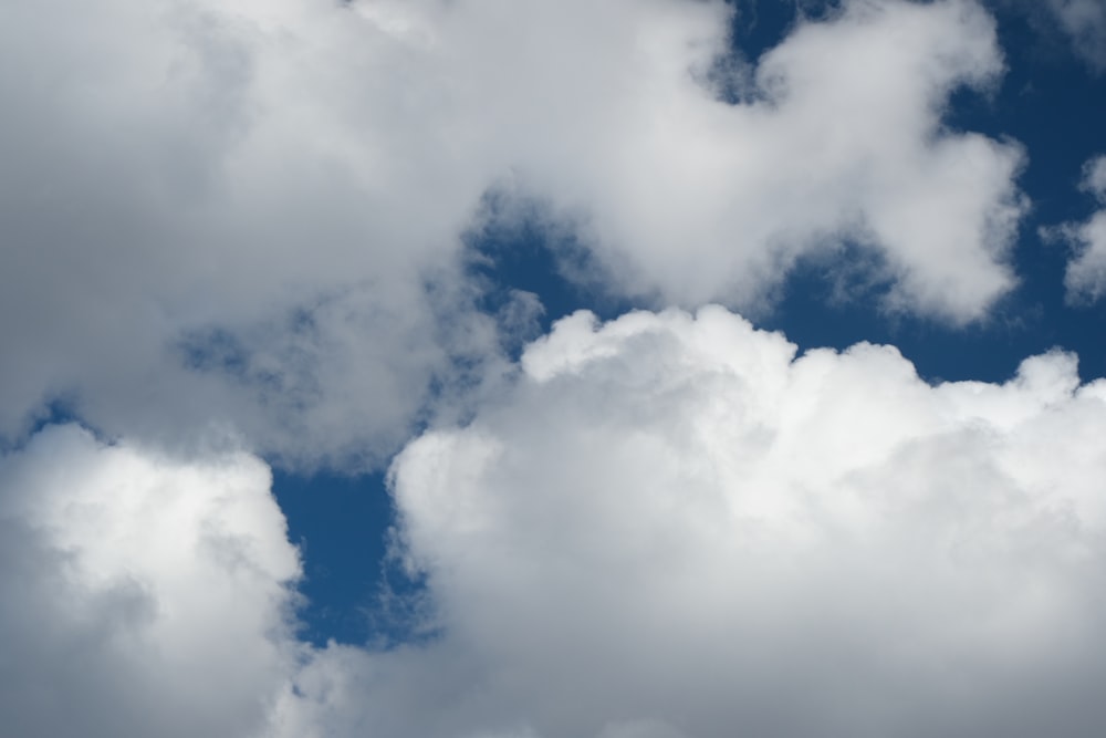 a plane flying through a cloudy blue sky