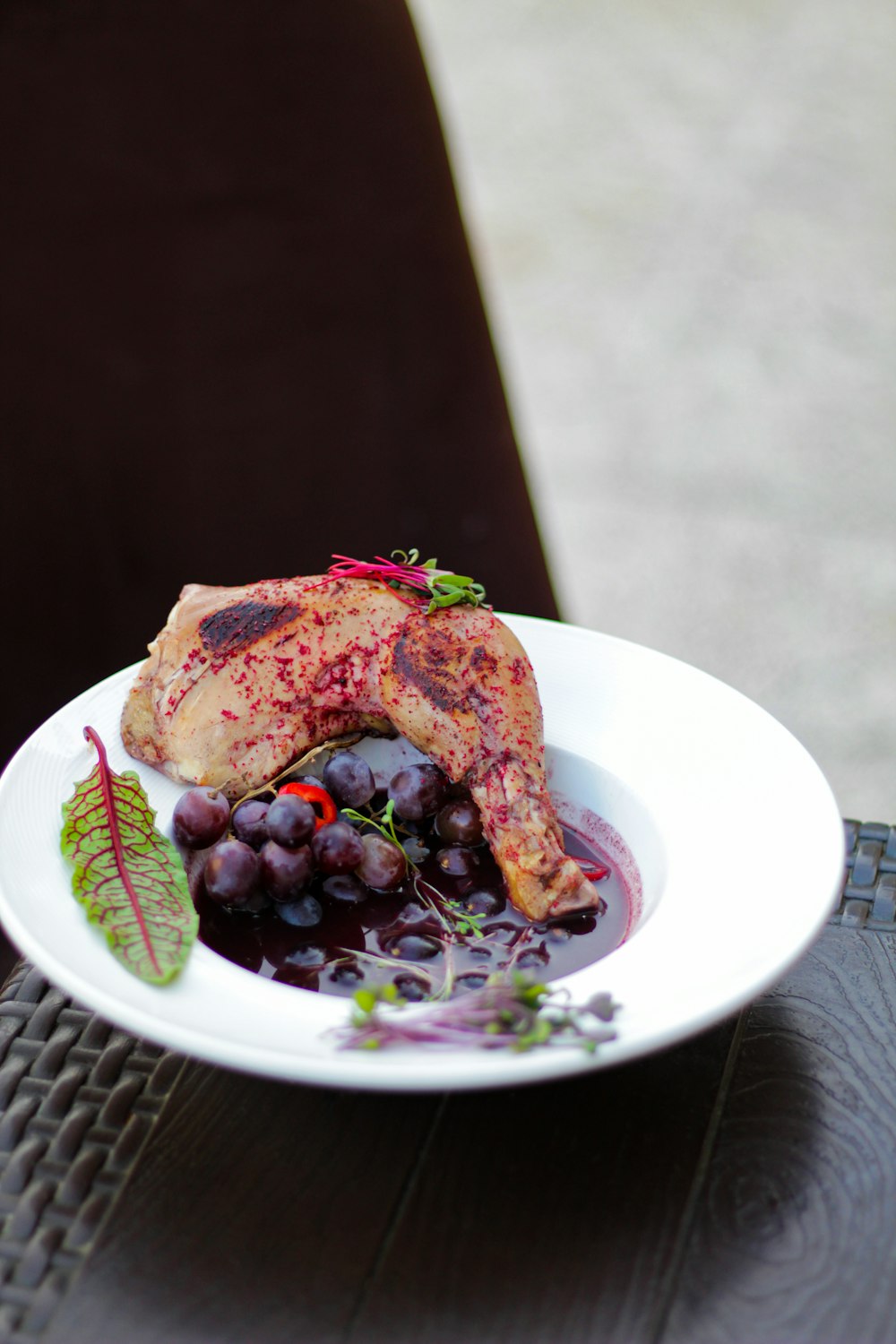 a white plate topped with meat and grapes