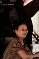 a woman sitting at a table smiling for the camera