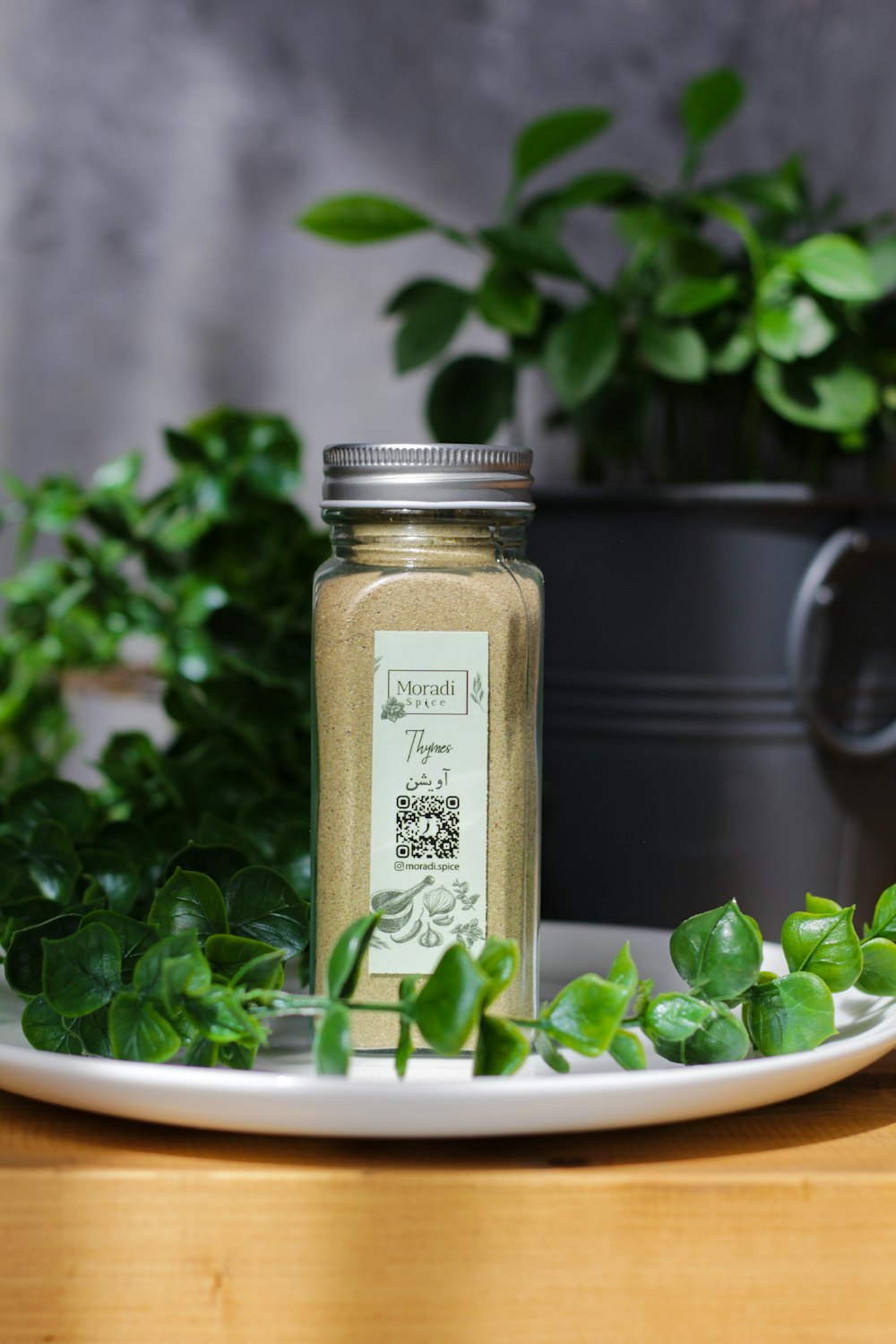 a jar of herbs sitting on a plate next to a potted plant