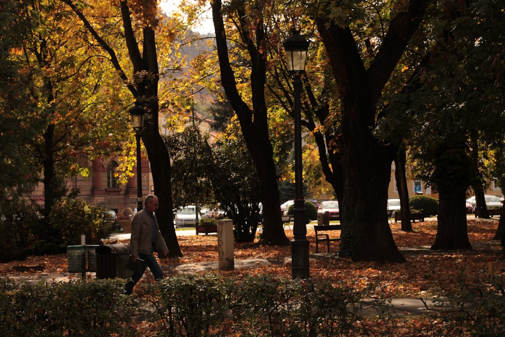 a man walking through a park in the fall