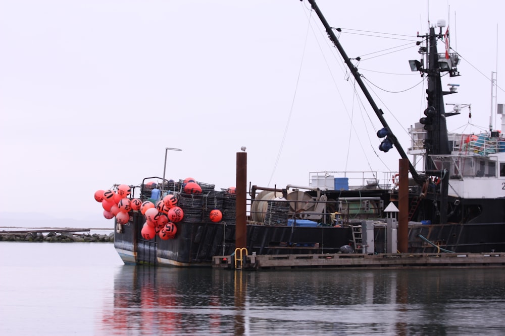 a boat docked at a pier with red balloons