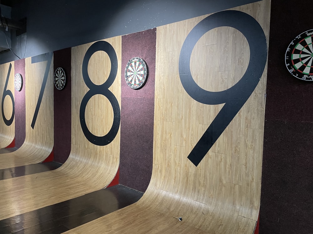 a wooden wall with numbers and darts on it