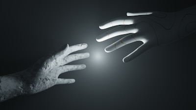 A stone-textured human hand reaches out towards a robotic hand with an illuminated point between them, set against a dark and minimalistic background.