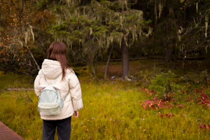 Lightweight puffer jacket packed into a small pouch resting on a forest trail during a chilly evening.