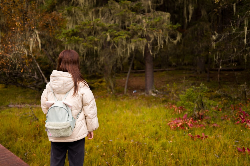 a young girl with a back pack walking in the woods