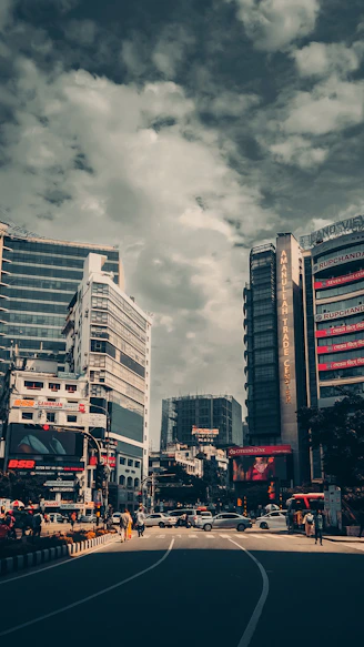 a city street filled with tall buildings under a cloudy sky