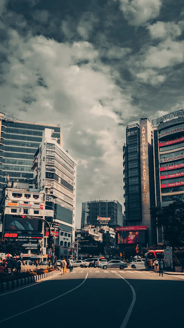 a city street filled with tall buildings under a cloudy sky