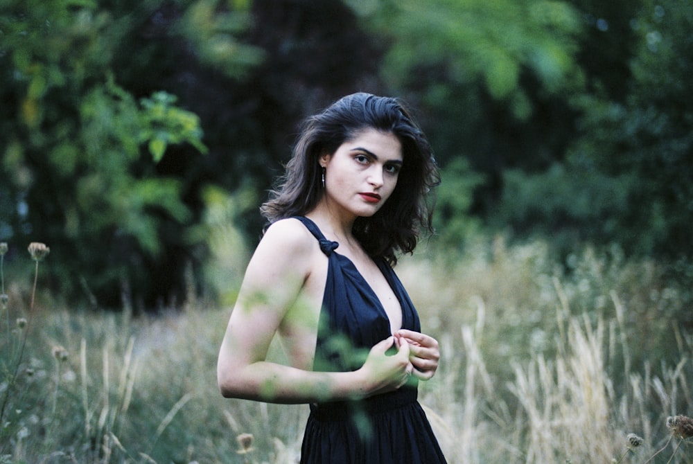 a woman in a black dress standing in a field