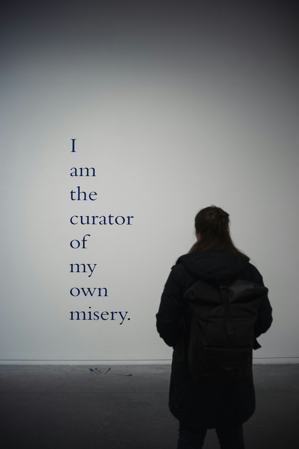 a woman standing in front of a wall with a quote on it