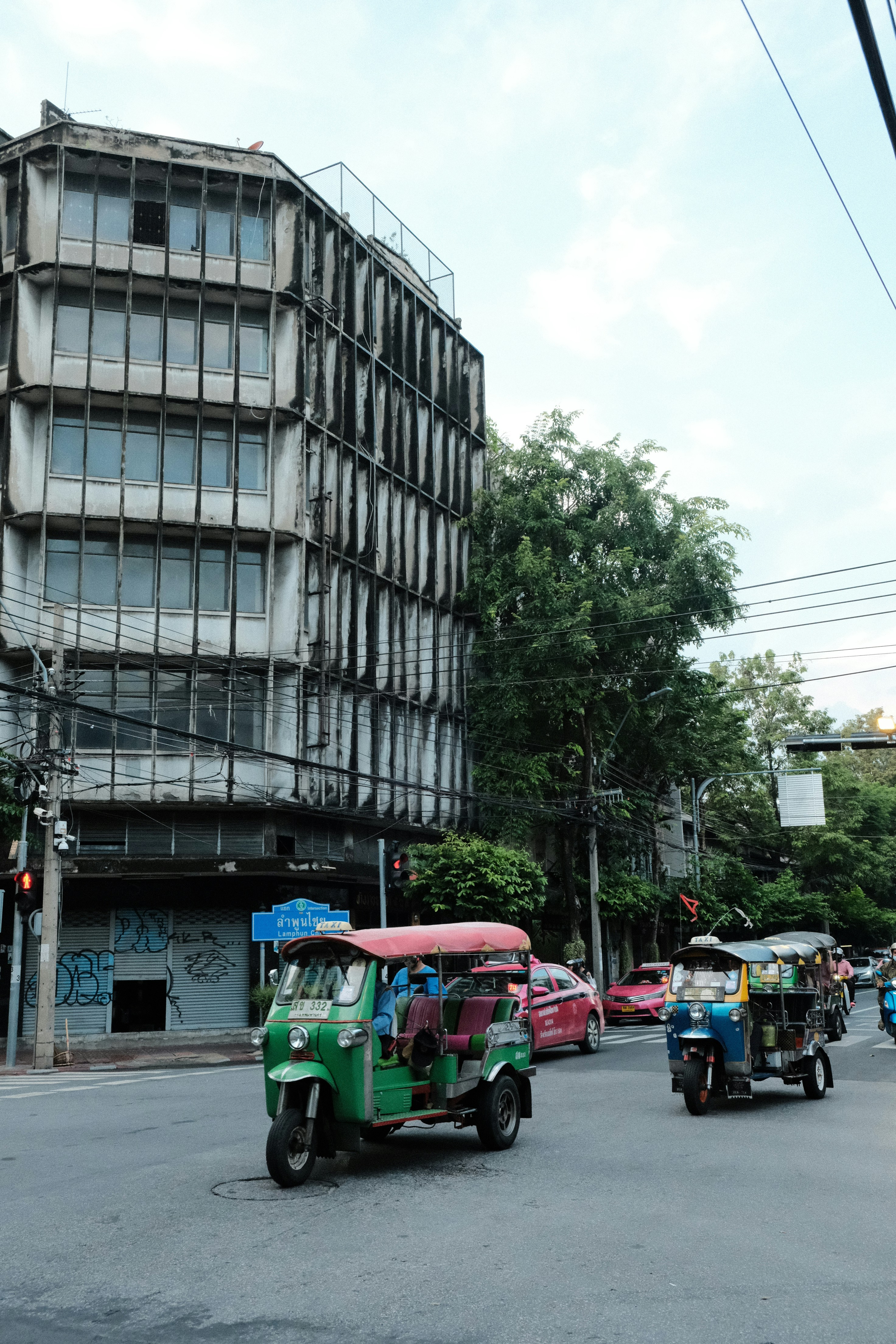 um grupo de carros dirigindo por uma rua ao lado de um prédio alto