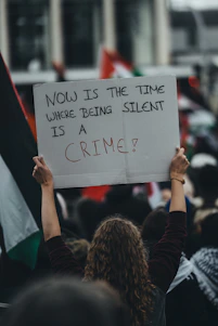a person holding a sign that says now is the time where being silent is a