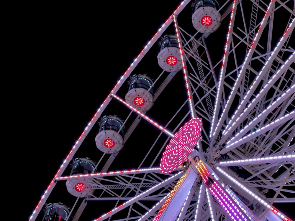 a ferris wheel lit up at night with red and white lights