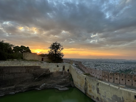 A dramatic dusk view of a Sicilian landscape with ancient stone walls and a fiery red sky.