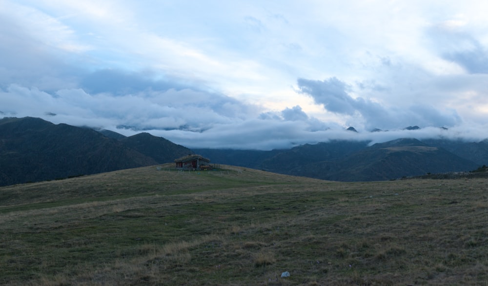 a grassy field with a house on top of it