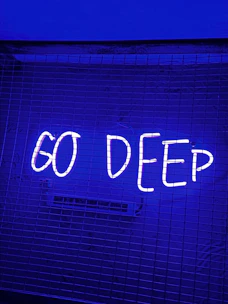 a neon sign that says go deep on a wall