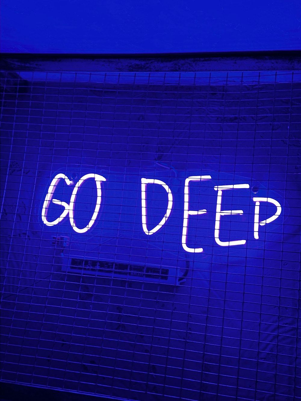 eine Leuchtreklame mit der Aufschrift "Go Deep" an einer Wand