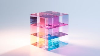 A transparent cube structure composed of smaller interlocking blocks, each reflecting and transmitting light in various hues of blue, pink, and purple. The arrangement of the cubes creates an abstract, geometric pattern with subtle reflections on the surface beneath.