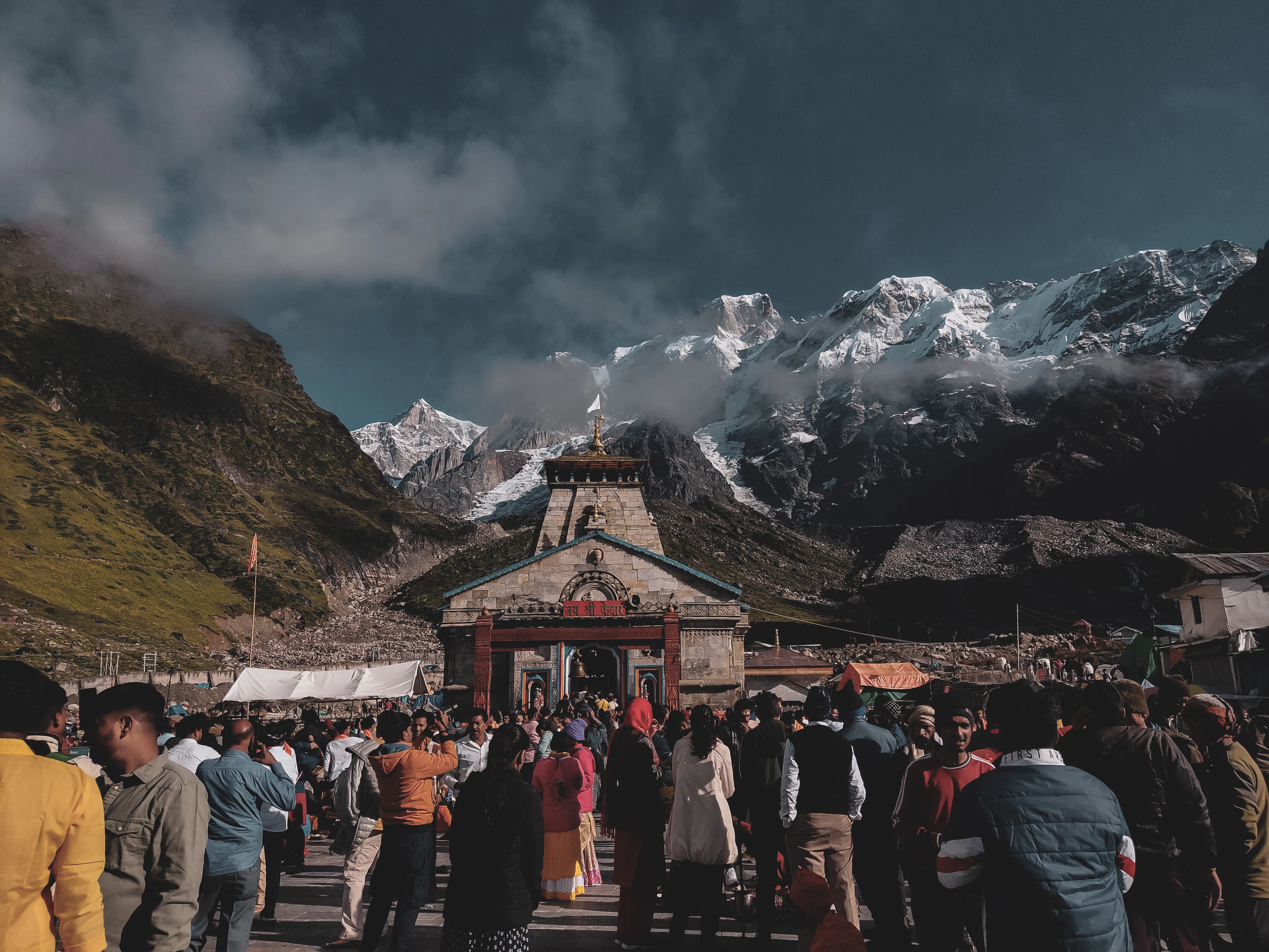 A crowd outside Kedarnath temple, below snow-capped peaks