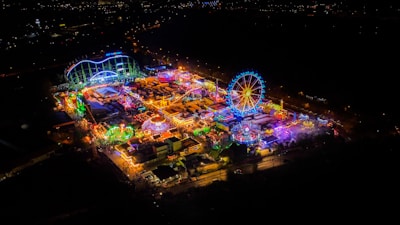 Night view of amusement park illuminated with warm lights.