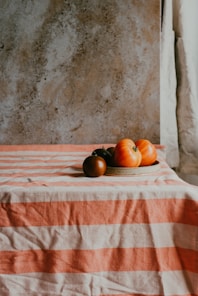 a plate of tomatoes on a striped tablecloth