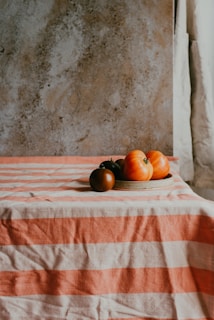 a plate of tomatoes on a striped tablecloth