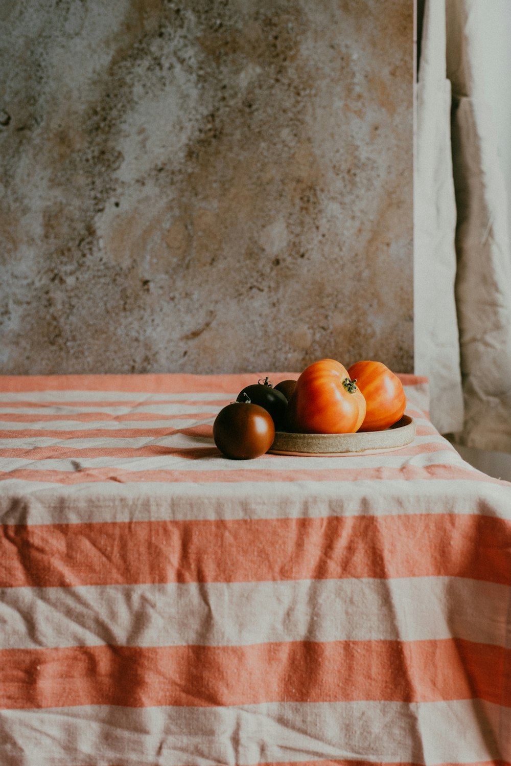 a plate of tomatoes on a striped tablecloth