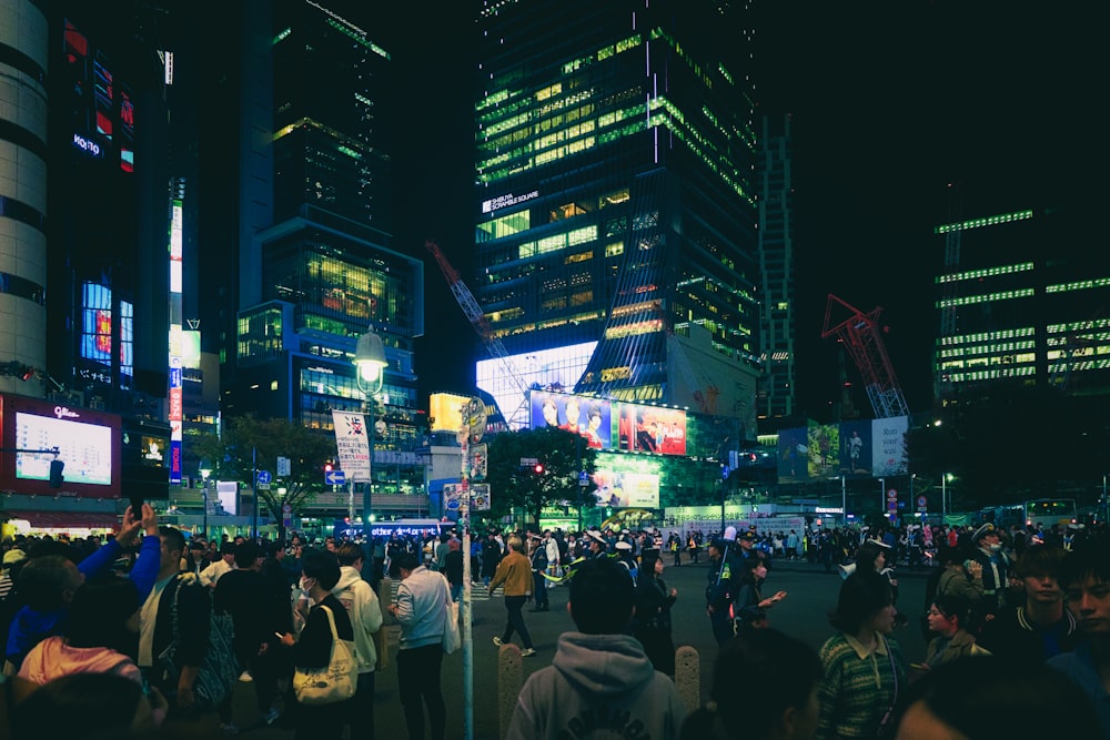 una multitud de personas de pie en una calle por la noche