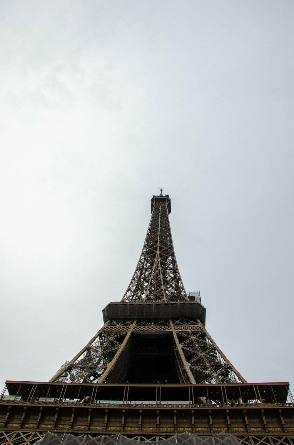 the top of the eiffel tower against a cloudy sky