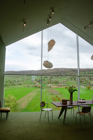 Comfortable guest room with large windows overlooking lush green vineyards.
