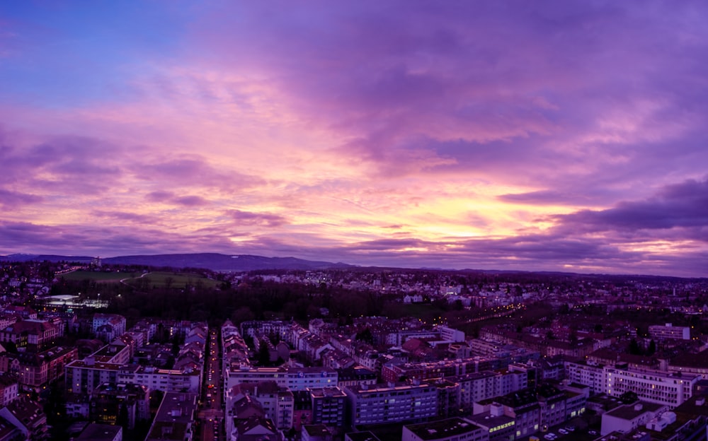 a view of a city at sunset with purple clouds