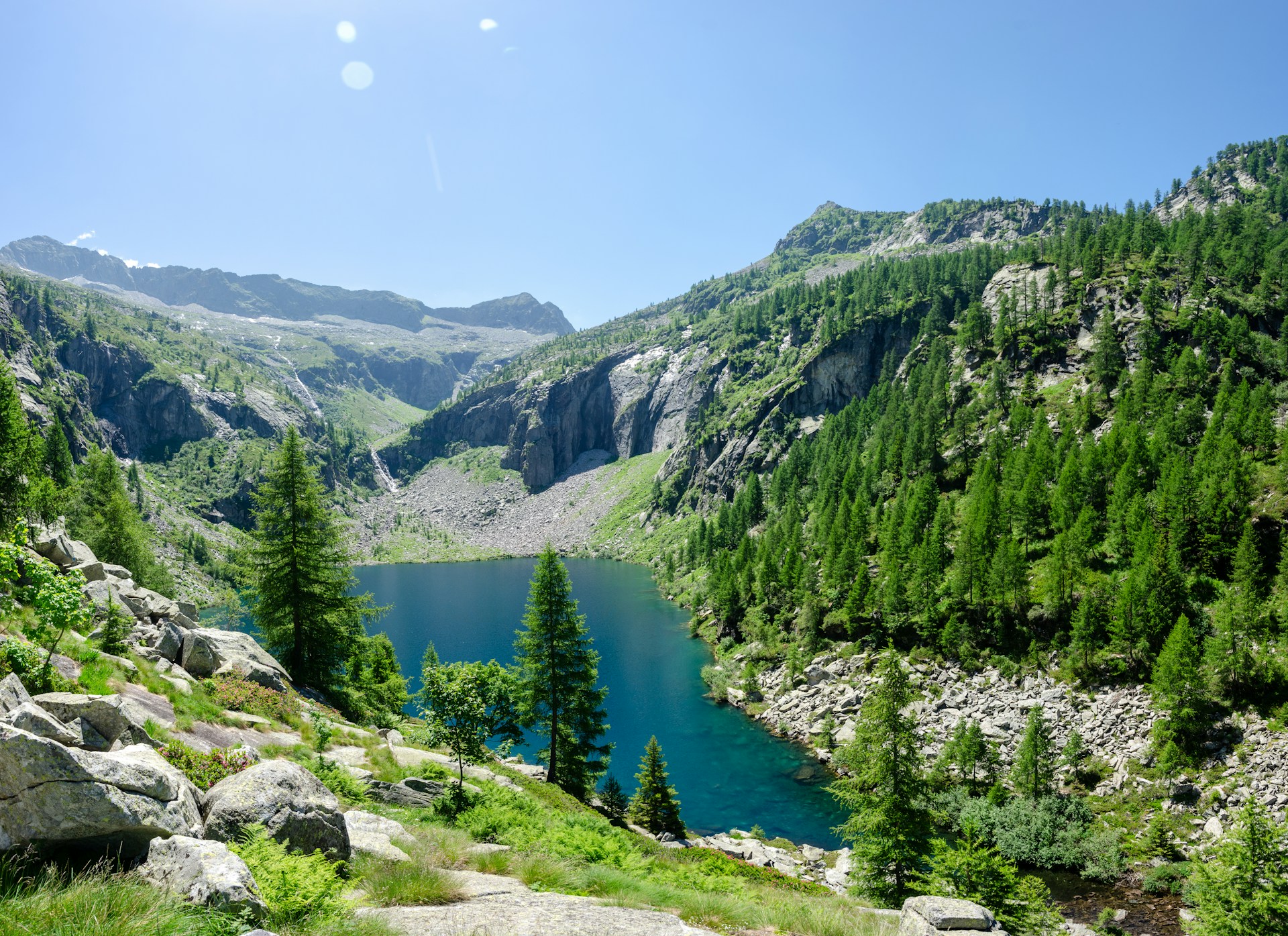 A peaceful mountain landscape in California, showcasing lush greenery and a clear blue sky from a high vantage point.