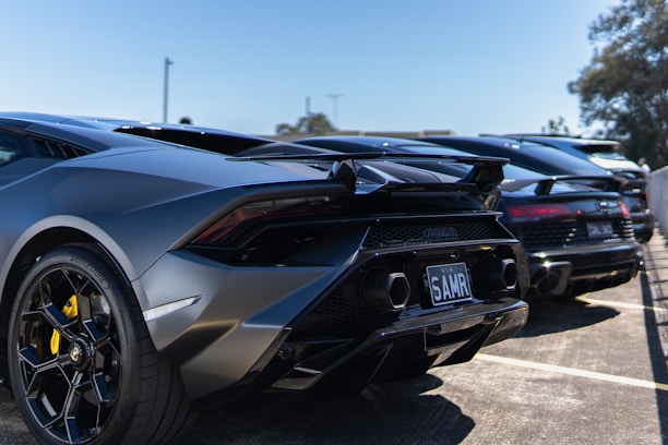 A sleek lineup of cars and motorcycles parked outside a modern dealership under clear skies.