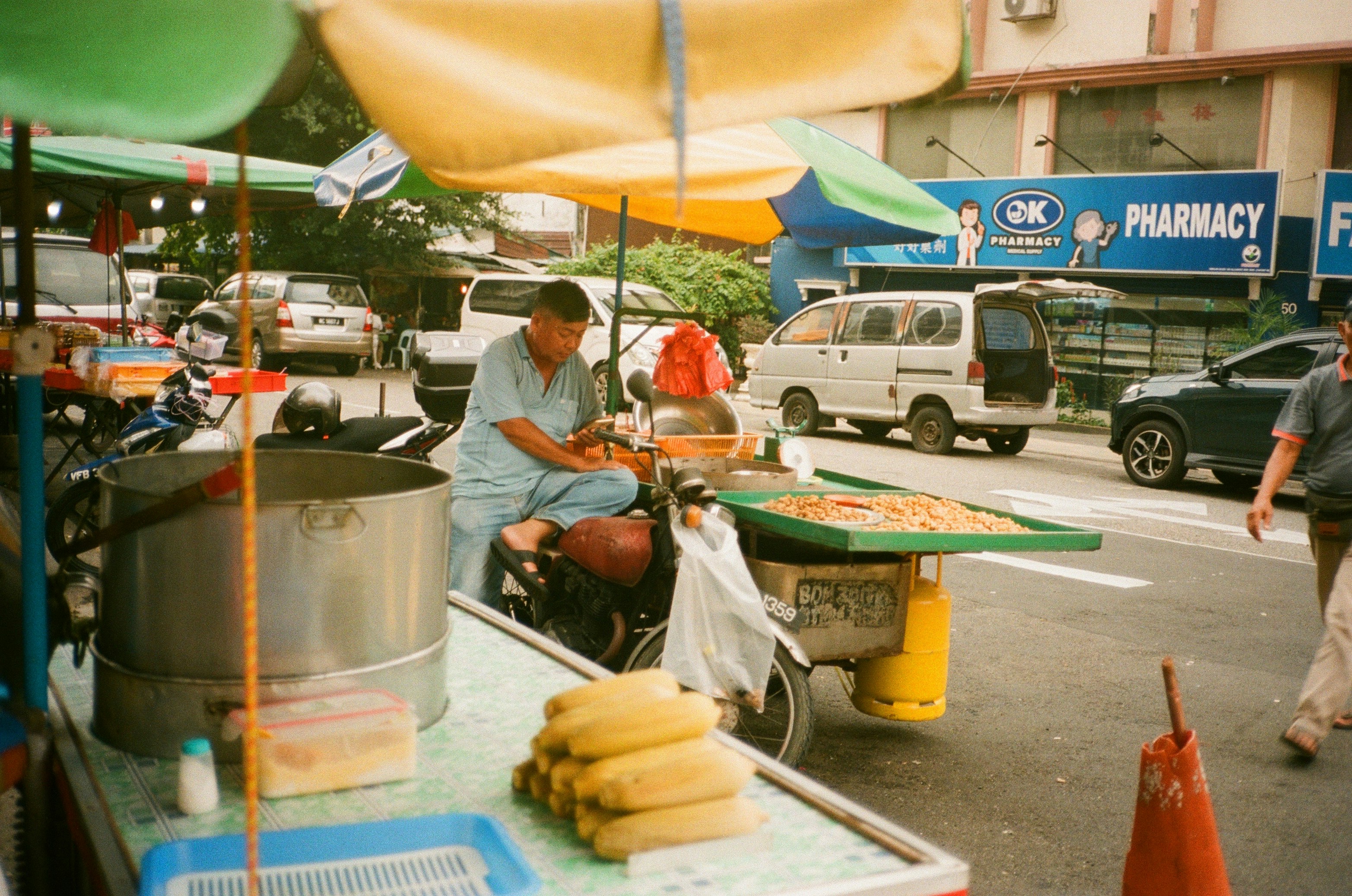 Scène de vie quotidienne montrant un vendeur ambulant préparant de la nourriture de rue à Pudu.