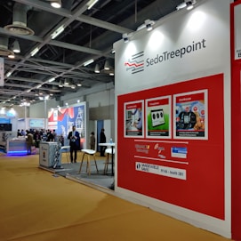 a red and white trade show booth with people standing around