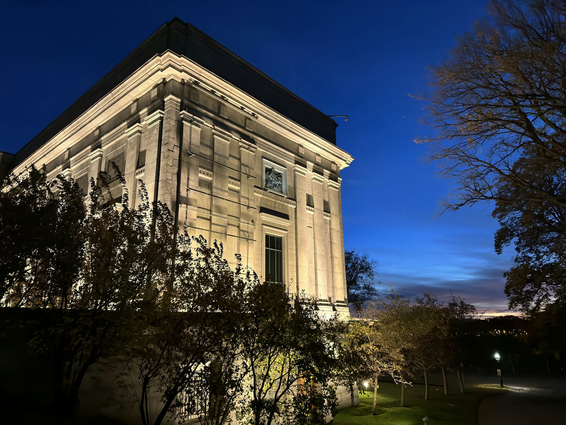 A twilight view of iluminatum residence's grand stone facade, softly lit to highlight its castle-like architecture.