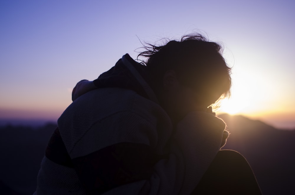 a silhouette of a person with the sun in the background