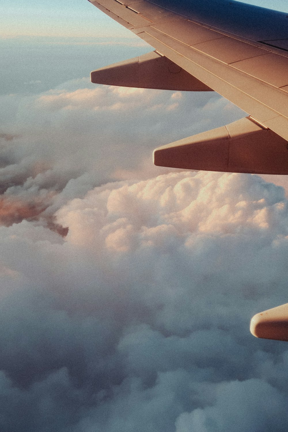 a view of the wing of an airplane above the clouds